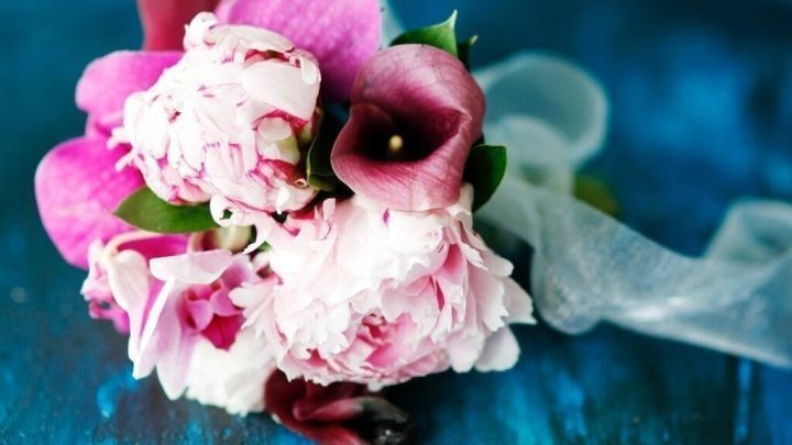 Ein bunter Blumenstrau&szlig; liegt auf einer blauen Oberfl&auml;che, bereit f&uuml;r den Transport im Auto zu einem besonderen Anlass.