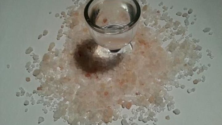 Eine klare Schale mit Wasser steht in der Mitte von grobem Salz, was auf ein Augenbad gegen gereizte Augen hinweist.