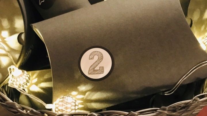 Schwarze, nummerierte P&auml;ckchen liegen in einem Korb und werden als Adventskalender f&uuml;r Weihnachtsgeschenke dekoriert.