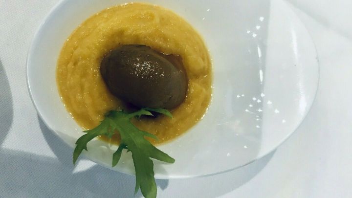 Ein cremiges S&uuml;&szlig;kartoffelp&uuml;ree in einer Sch&uuml;ssel, garniert mit einem Schokoladeneis und frischen Kr&auml;utern.