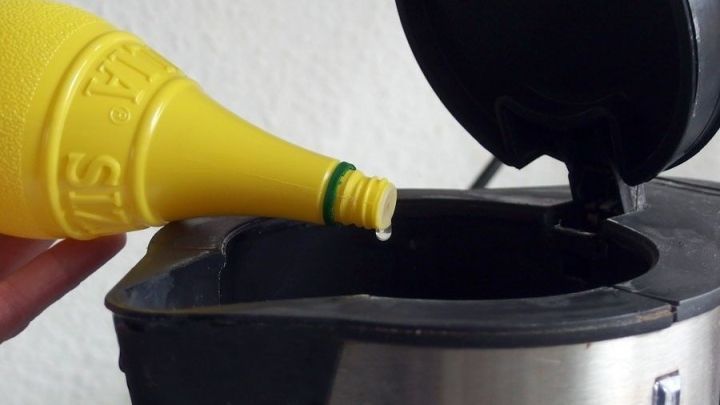 Ein gelber Flaschenverschluss wird &uuml;ber die &Ouml;ffnung eines Wasserkochers gehalten, um Kalkfreiheit zu gew&auml;hrleisten.