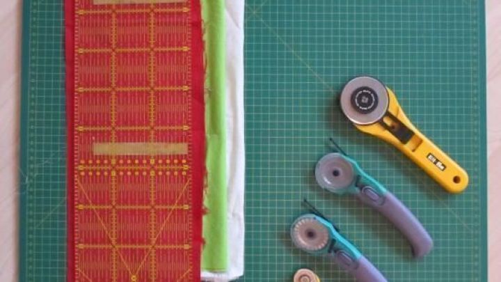 Ein Rollschneider schneidet pr&auml;zise Papier auf einer gr&uuml;nen Schneidematte, w&auml;hrend Lineale und verschiedene Werkzeuge daneben liegen.