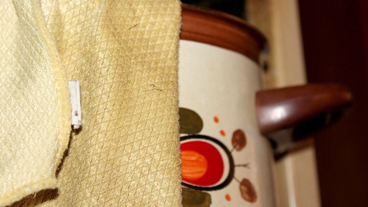 Ein gelbes Sp&uuml;ltuch h&auml;ngt &uuml;ber einem Topf mit ansprechendem Design, w&auml;hrend es bereit zum Auskochen ist.