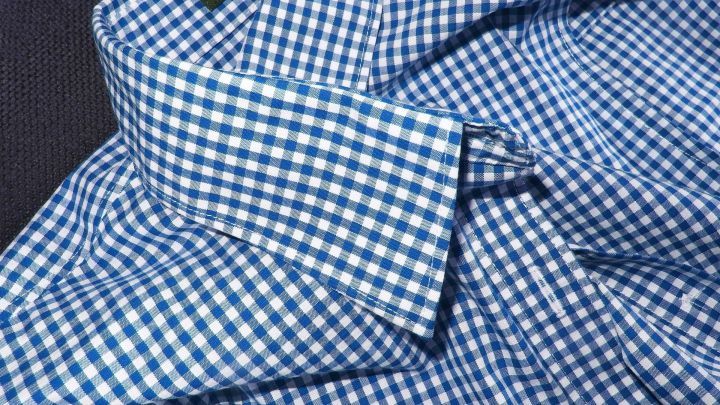 Ein kariertes Hemd mit einem auff&auml;lligen Kragen liegt auf einer dunklen Oberfl&auml;che, bereit zum Reinigen von Kragenschmutz und Deoflecken.