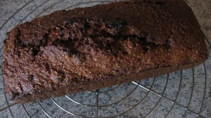 Ein frisch gebackenes Kleiebrot liegt auf einem Kuchengitter, bereit zum Genie&szlig;en mit Honig und Aprikosen.