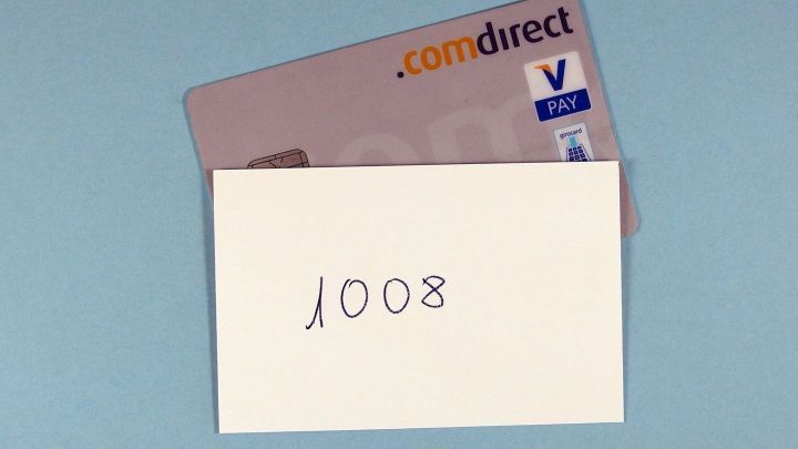 Eine Karte liegt neben einem Zettel mit der Geheimzahl "1008", auf einem blauen Hintergrund.