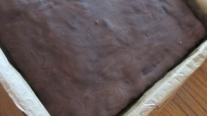 Ein saftiger Nusskuchen mit Zucchini liegt in einer Backform auf einem Holztisch und wartet auf den Genuss.