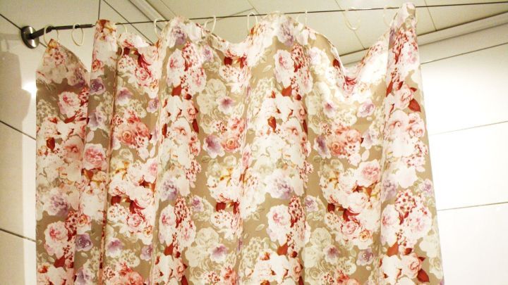 Ein blumenmuster Duschvorhang h&auml;ngt in der Dusche und verdeckt den Bereich, der f&uuml;r das Duschen genutzt wird.