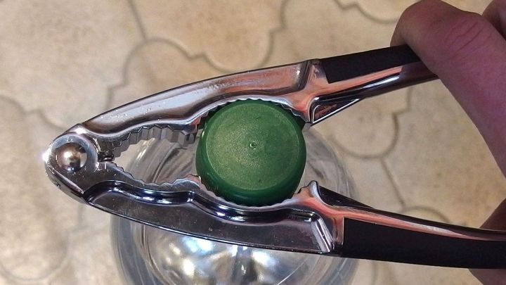 Eine Flasche mit Drehverschluss wird mit einem speziellen &Ouml;ffner in einer K&uuml;che ge&ouml;ffnet, um den Inhalt zug&auml;nglich zu machen.