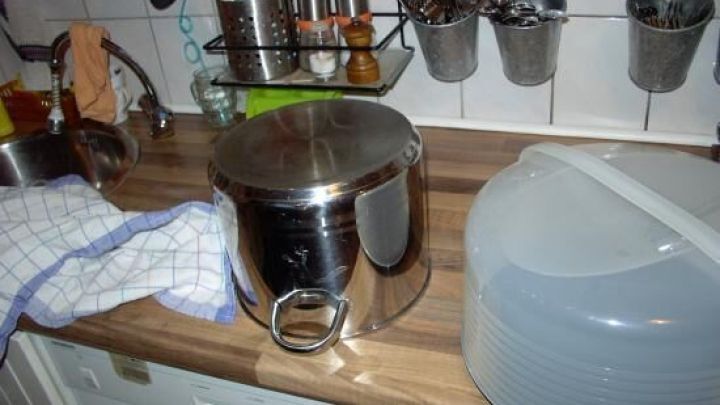 Auf der Arbeitsplatte in einer K&uuml;che steht eine silberne Torte-Box und ein Kunststoffdeckel, bereit zum Dekorieren.