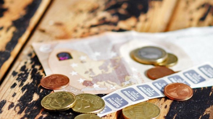 M&uuml;nzen und Geldscheine sind auf einem Holzuntergrund verteilt, was eine Auszahlung von Bonuspunkten symbolisiert.