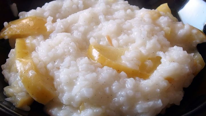 Ein cremiger Apfelreis ist in einer schwarzen Sch&uuml;ssel angerichtet, mit St&uuml;cken von &Auml;pfeln und einer angenehmen Konsistenz.