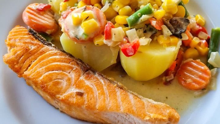 Saftiger Lachs liegt neben Gem&uuml;se und Kartoffeln auf einem Teller, ideal zum Genie&szlig;en und Gr&auml;ten entfernen.