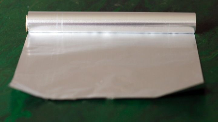 Eine Rolle Alufolie liegt flach auf einer gr&uuml;nen Oberfl&auml;che und k&ouml;nnte zur Linderung von Phantomschmerzen verwendet werden.