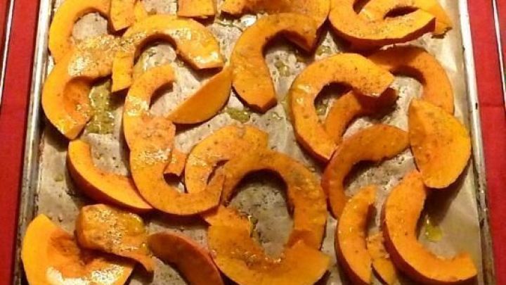 Gebackene K&uuml;rbisscheibchen liegen auf einem Blech, goldbraun und appetitlich, bereit zur Zubereitung von Feldsalat.