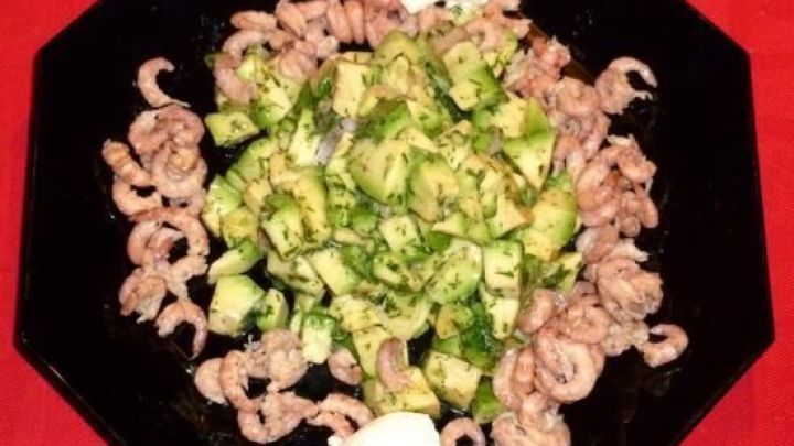 Gr&uuml;ne Avocadow&uuml;rfel liegen auf einem schwarzen Teller, umrahmt von Nordseekrabben, serviert in einer frischen Zitronen-Dillsauce.