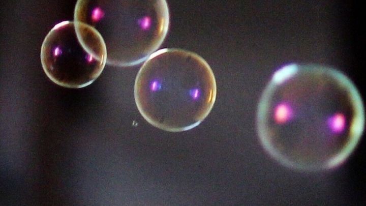 Seifenblasen schweben sanft durch die Luft, schimmernd und in verschiedenen Gr&ouml;&szlig;en, vor einem unscharfen Hintergrund.