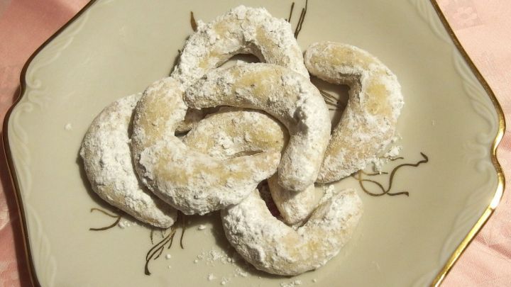 Auf einem eleganten Teller liegen mehrere Vanillekipferl, die mit Puderzucker best&auml;ubt sind und appetitlich aussehen.