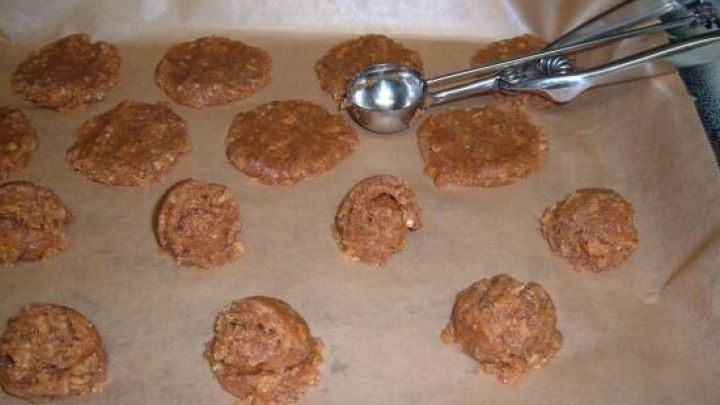 Ein Eisportionierer formt gleichm&auml;&szlig;ige Keksteigportionen auf einem Backblech mit Backpapier in einer K&uuml;che.