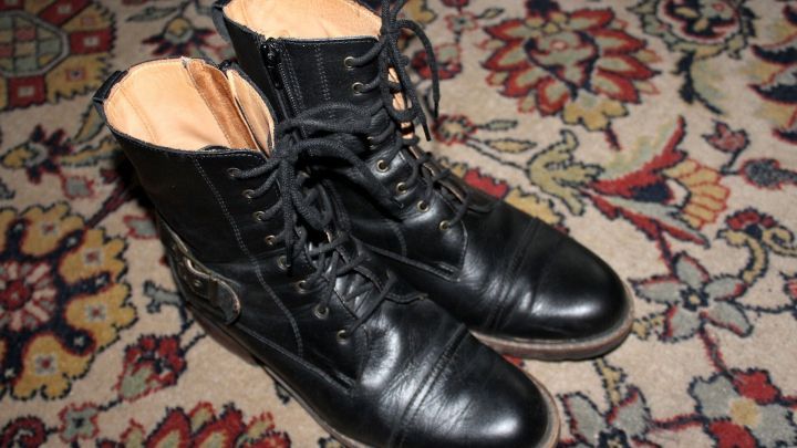 Schwarze Schuhe stehen auf einem gemusterten Teppich, bereit f&uuml;r das Dehnen, um besser zu passen und bequemer zu sein.