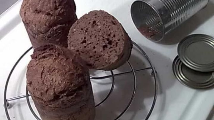 Dosenbrot steht auf einem Gitter zu k&uuml;hlen, w&auml;hrend leere Dosen und Deckel daneben auf einer wei&szlig;en Oberfl&auml;che liegen. &copy;Cally