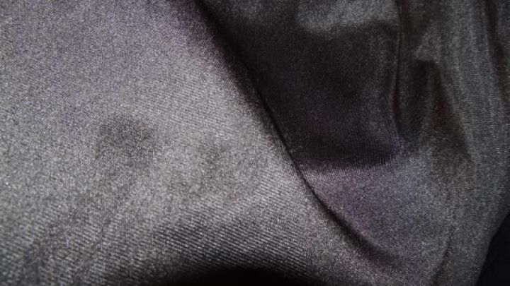 Schwarze Seident&uuml;cher liegen zusammen, leicht gefaltet, in einem dunklen Umfeld, umgeben von sanften Schatten.