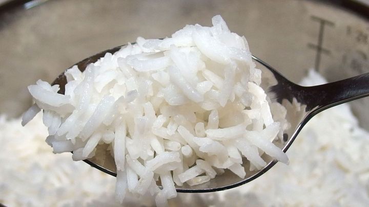 Wei&szlig;e Reisk&ouml;rner befinden sich in einem L&ouml;ffel, der bereit ist, einem Hund bei Durchfall zu helfen.