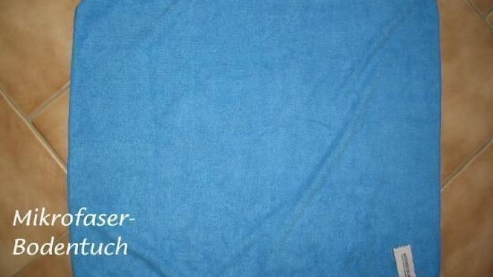 Ein blaues Mikrofasertuch liegt flach auf einem gefliesten Boden und ist bereit, beim Wischen nicht zu verrutschen.