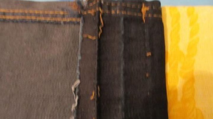 Eine Jeans wird gek&uuml;rzt und umgen&auml;ht, liegend auf einem B&uuml;gelbrett mit blau-gelbem Bezug.