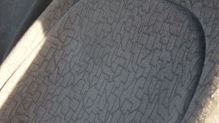 Ein Autopolster mit unregelm&auml;&szlig;iger Oberfl&auml;che liegt im Sonnenlicht, zeigt Abnutzungserscheinungen und k&ouml;nnte eine Reinigung ben&ouml;tigen.