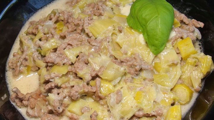 Eine Hack-Lauch-Pfanne zeigt eine Mischung aus Hackfleisch und Lauch in einer cremigen Sauce, garniert mit frischem Basilikum.