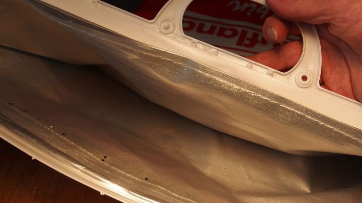 Eine Person h&auml;lt einen K&uuml;belpflanzen-Schutz &uuml;ber eine Pflanze, um sie vor K&auml;lte zu bewahren.