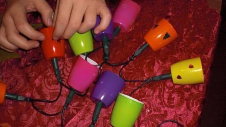 Bunte Fruchtzwergbecher werden gerade zu einer Lichterkette verbunden, um festliche Stimmung zu erzeugen.