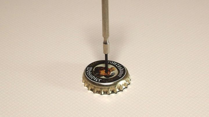 Ein Schraubenzieher bewegt sich, um einen Seifenhalter zu befestigen, der auf einer flachen Oberfl&auml;che liegt.