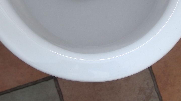 Ein WC-Becken mit gelben Ablagerungen unter dem Rand, umgeben von Fliesen in einem Badezimmer.