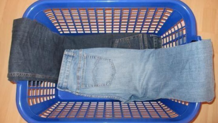 Gestapelte Hosen liegen ordentlich in einem blauen W&auml;schekorb, bereit zum faltenfreien Packen f&uuml;r die Reise.