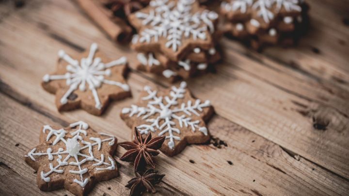 Leckere Duftsterne aus Lebkuchen liegen auf einer rustikalen Holzoberfl&auml;che, umgeben von Zimtstangen und Sternanis.