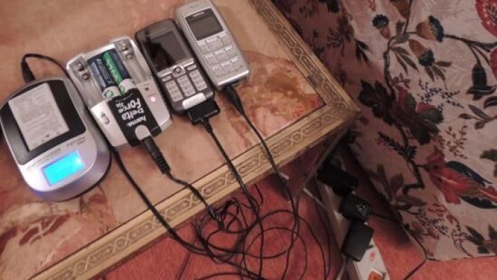 Akkuladeger&auml;t l&auml;dt mehrere Ger&auml;te mit einer Steckerleiste, die an einen Tisch in einem wohnlichen Raum angeschlossen ist.