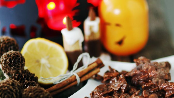 Auf einem rustikalen Holztisch liegen selbstgemachte Schokocrossies neben Zimtstangen und einer Zitrone, umgeben von festlicher Dekoration.