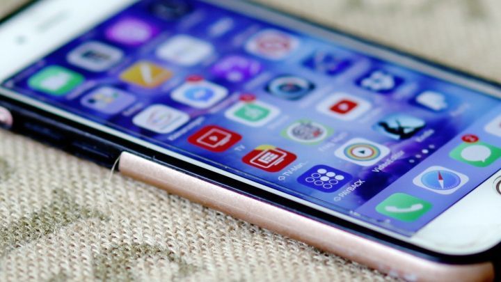 Ein iPhone liegt auf einem Tisch und zeigt die voreingestellten Apps auf dem Bildschirm in einer ansprechenden Anordnung.