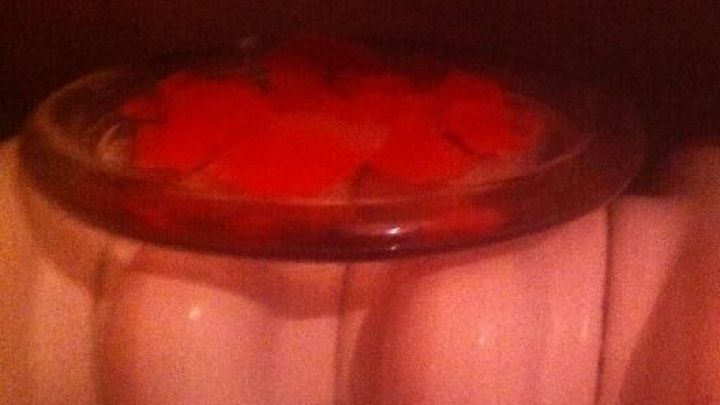 Ein Glas mit geschmolzenem Wachs von Duftkerzen steht auf einer Heizung und k&uuml;hlt in einer warmen Umgebung ab.