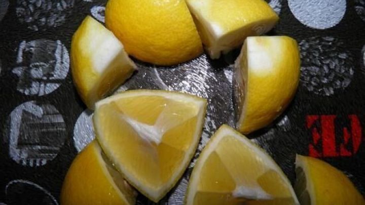 Zitronenh&auml;lften liegen motiviert auf einem dunklen Tisch, bereit zum Haltbar machen durch Einlegen.