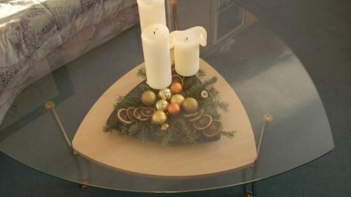 Auf einem Tisch steht eine Adventsdeko mit Kerzen und bunten Kugeln, umgeben von einer gem&uuml;tlichen Wohnzimmeratmosph&auml;re.