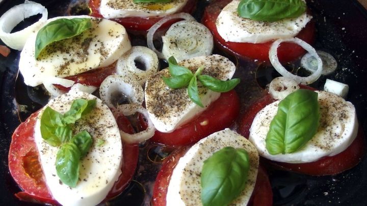 Frische Tomatenscheiben mit Mozzarella und Basilikum werden in Oliven&ouml;l gew&uuml;rzt, ideal f&uuml;r einen gesunden Tipp zum Abnehmen.