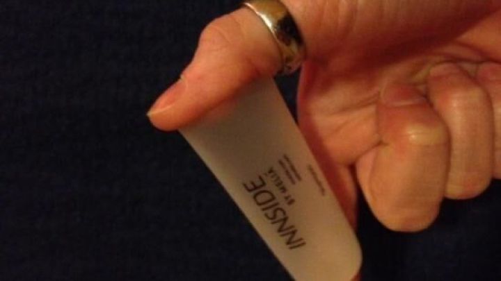 Ein Hand h&auml;lt eine selbst gemachte Nasendusche, die zur Anwendung bereit ist, vor einem dunklen Hintergrund.