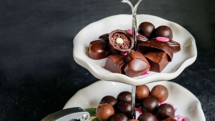 Krokantpralinen sind auf einer eleganten Etagere platziert, umgeben von einer dunklen, ansprechenden Hintergrundfarbe.