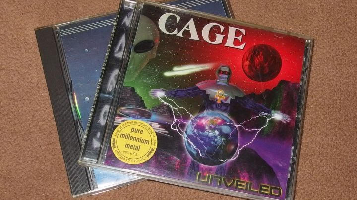 Ein CD-Case mit dem Titel "CAGE" liegt auf einem Tisch neben einem anderen CD-Case, ideal f&uuml;r den Austausch von Musik-CDs.
