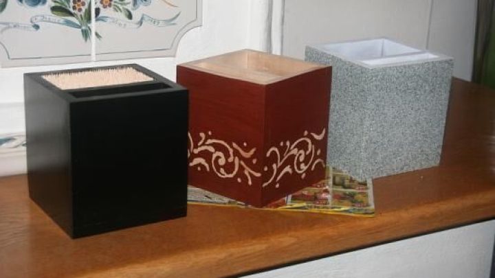 Drei Messerbl&ouml;cke stehen nebeneinander auf einer Holzoberfl&auml;che; der rote hat ein filigranes Muster, die anderen sind schlicht.