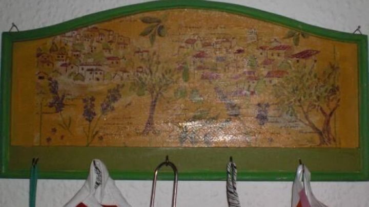 Ein dekoratives Wandbild mit einer l&auml;ndlichen Landschaft und verschiedenen B&auml;umen h&auml;ngt &uuml;ber mehreren h&auml;ngenden Servietten.