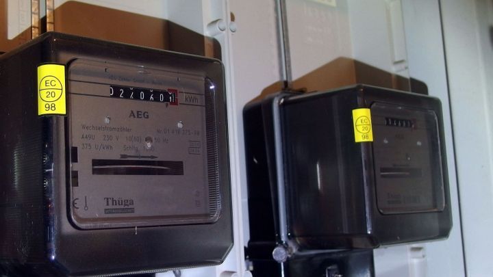 Zwei Stromverbrauchsmesser sind an einer Wand montiert und zeigen verschiedene Verbrauchsdaten in einem Technikraum an.